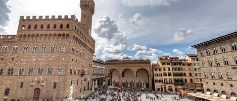 A historic square with a prominent tower and a fountain.