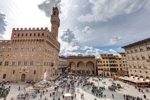Una plaza histórica con una torre destacada y una fuente.