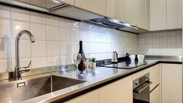 A modern kitchen with stainless steel appliances, a double sink, and a clean, tiled backsplash.