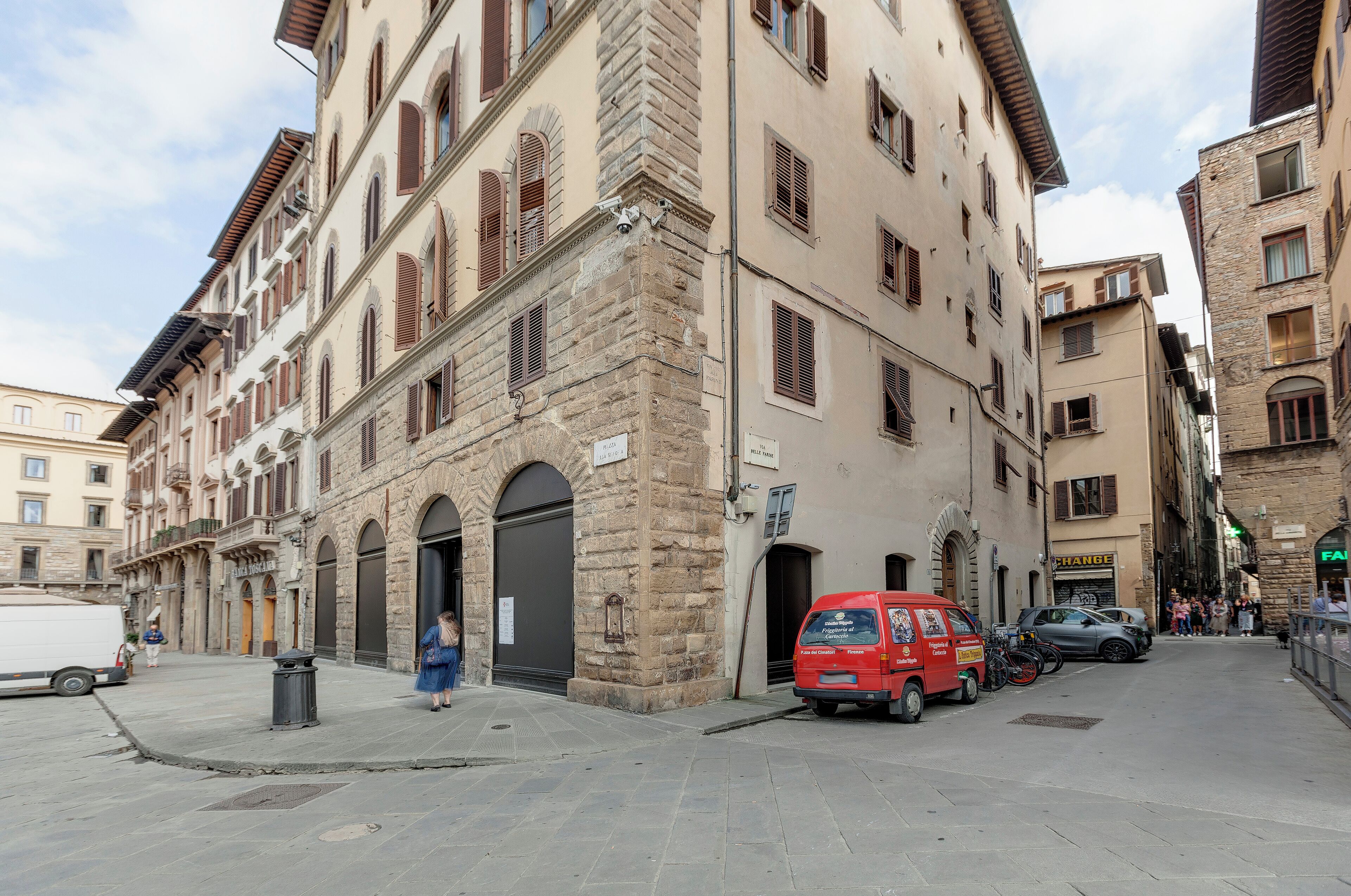 Una calle estrecha con edificios históricos, una camioneta roja y una camioneta blanca estacionadas al lado.