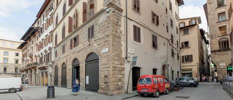 Una calle estrecha con edificios históricos, una camioneta roja y una camioneta blanca estacionadas al lado.