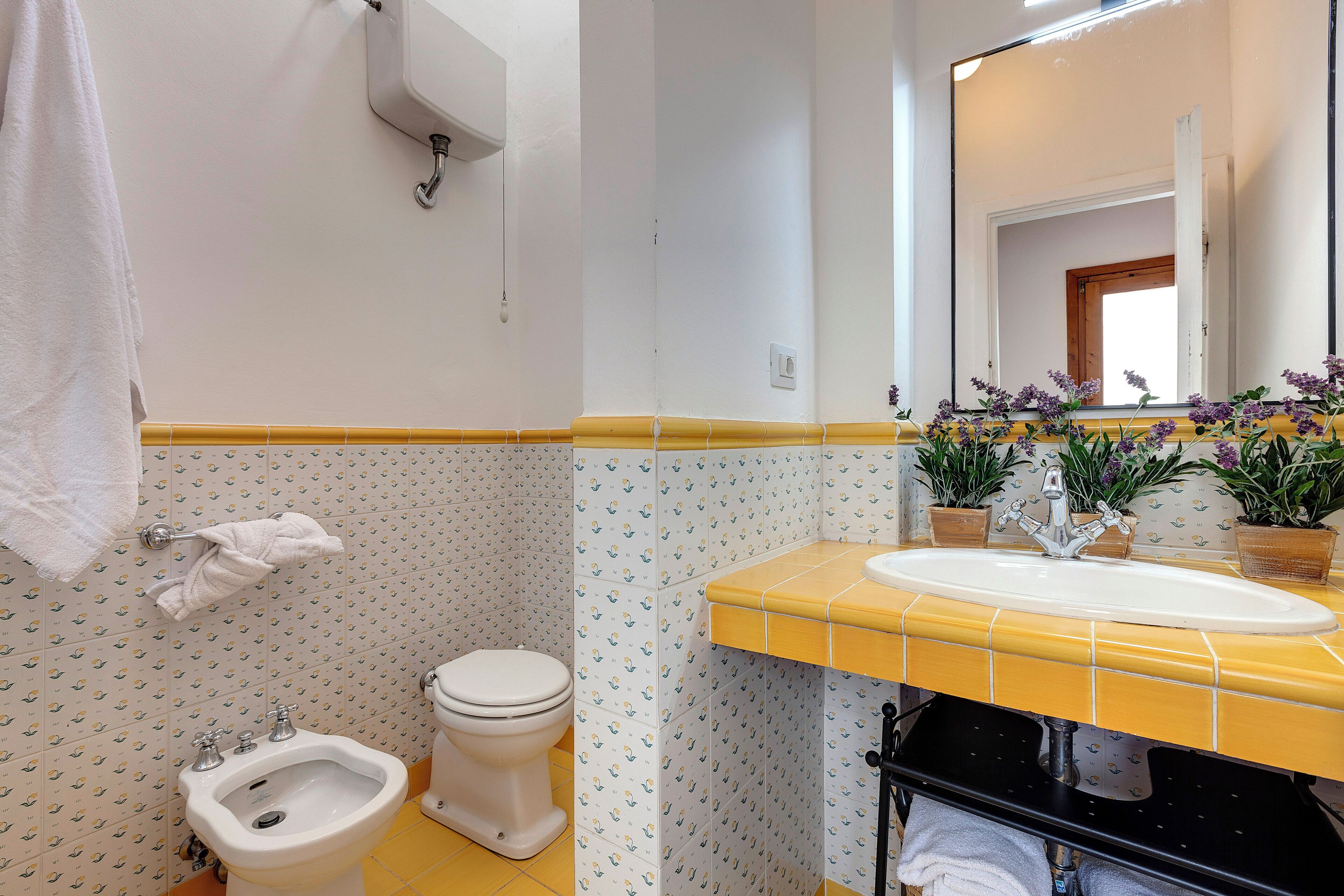 A bathroom with a toilet, bidet, sink, and mirror.
