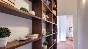 A hallway with wooden shelves holding books and potted plants. - Mamo Florence - Maddalena Apartment (Florence)