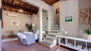 A bedroom with a bed, a desk, a chair, and a staircase leading to another room. - Mamo Florence - Magazzini Apartment (Florence)