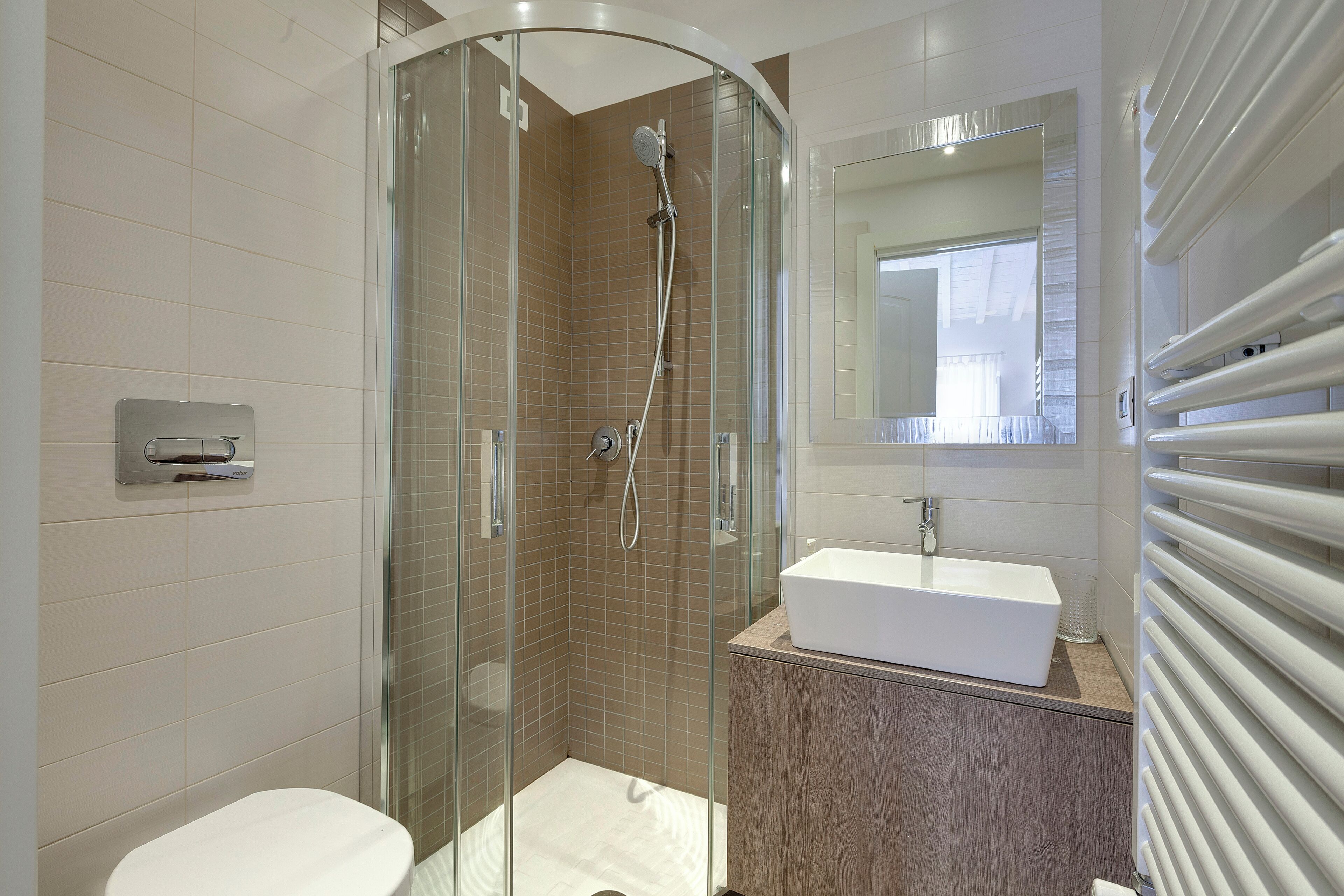 Une salle de bain moderne avec une douche à parois de verre, un lavabo blanc et un miroir au-dessus.