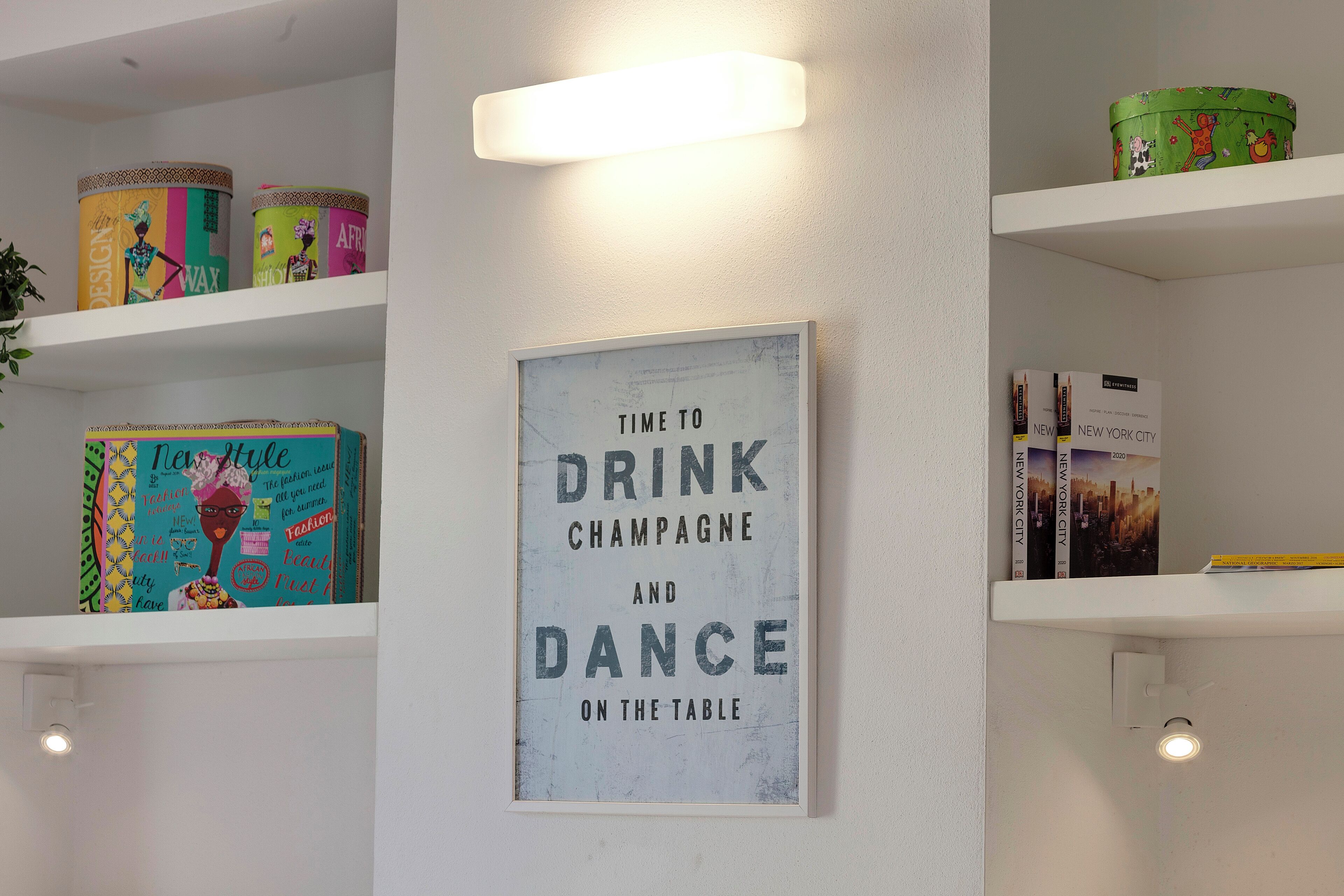 A wall with a framed sign that reads "Time to Drink Champagne and Dance on the Table."