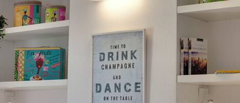 A wall with a framed sign that reads "Time to Drink Champagne and Dance on the Table."