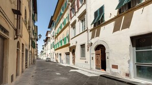 A narrow street lined with historic buildings featuring arched doorways and traditional shutters. - Mamo Florence - Margot Apartment (Florence)