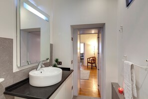 A modern bathroom with a round sink, a mirror, and a towel rack. - Mamo Florence - Oriuolo Apartment (Florence)