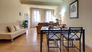 Ein großzügiger Wohnbereich mit einer Couch, Esstisch, Stühlen und einem großen Fenster mit Vorhängen.