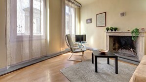 Ein Wohnzimmer mit Kamin, Fernseher und einem Sessel.
