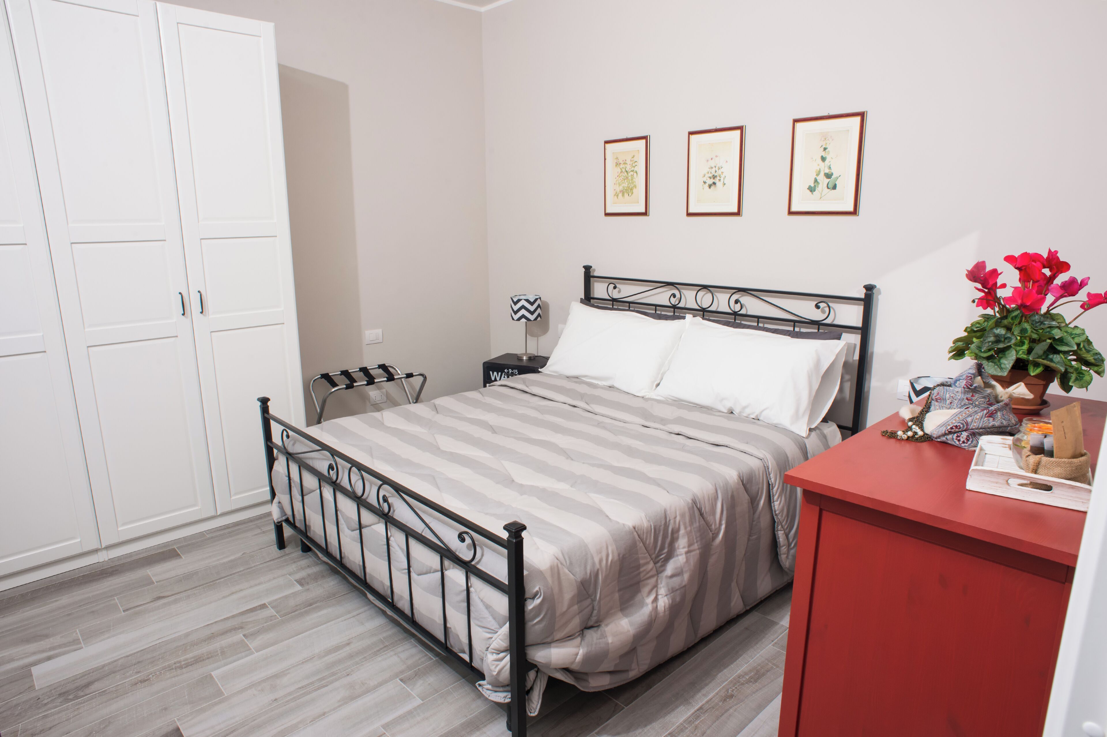 A bedroom with a bed, a nightstand, a dresser, and a wardrobe.