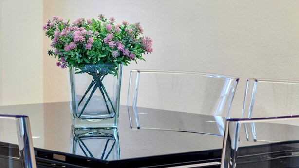 A clear glass table with a vase of pink flowers. - Mamo Florence - Pinti Apartment (Florence)