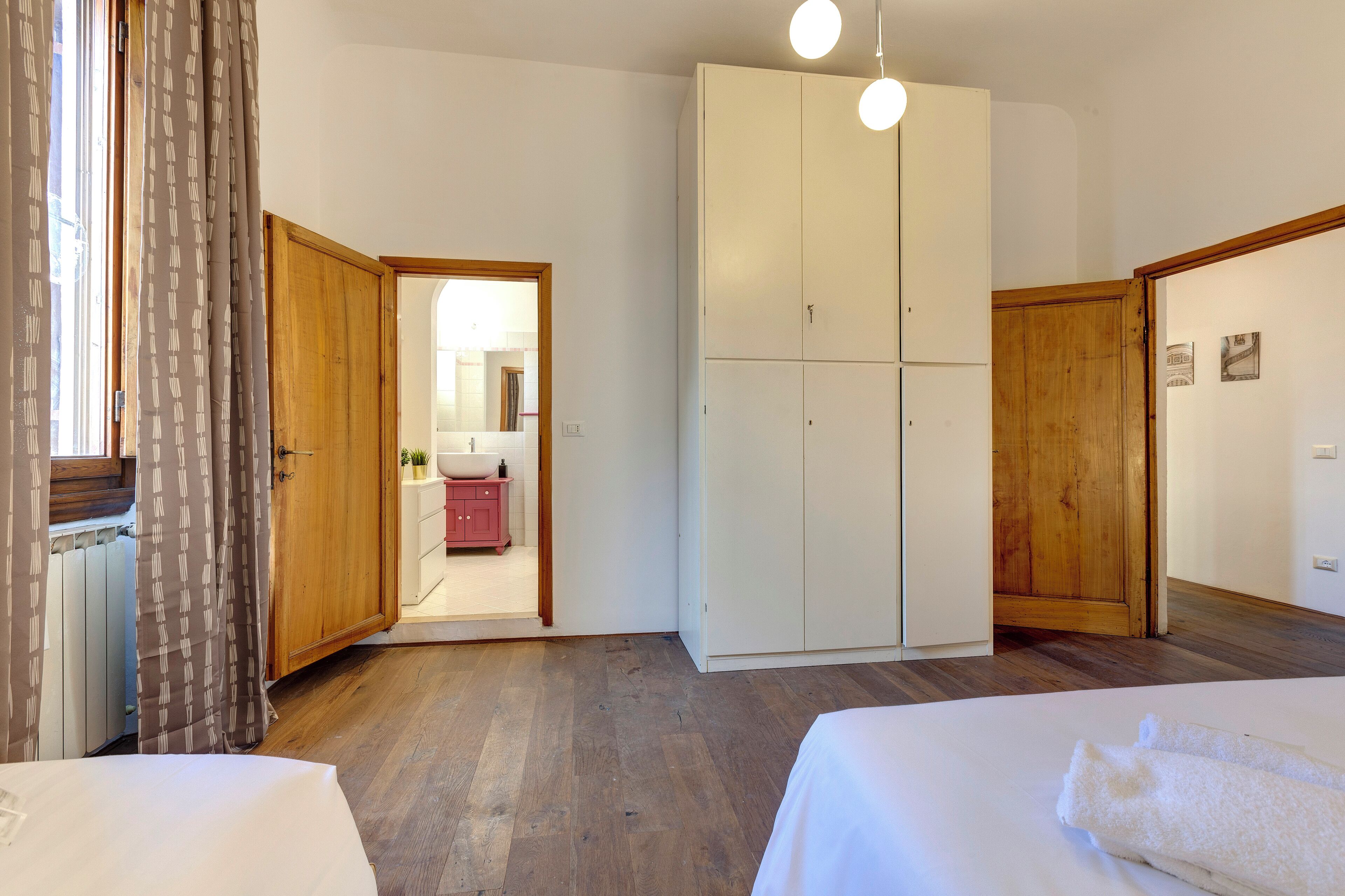 A bedroom with a large wardrobe, a bed, and a bathroom visible through an open door.