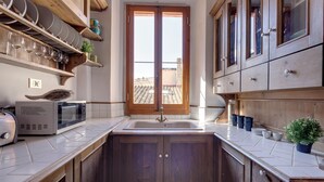 A kitchen with wooden cabinets, a microwave, a toaster, and a window with a view of buildings.