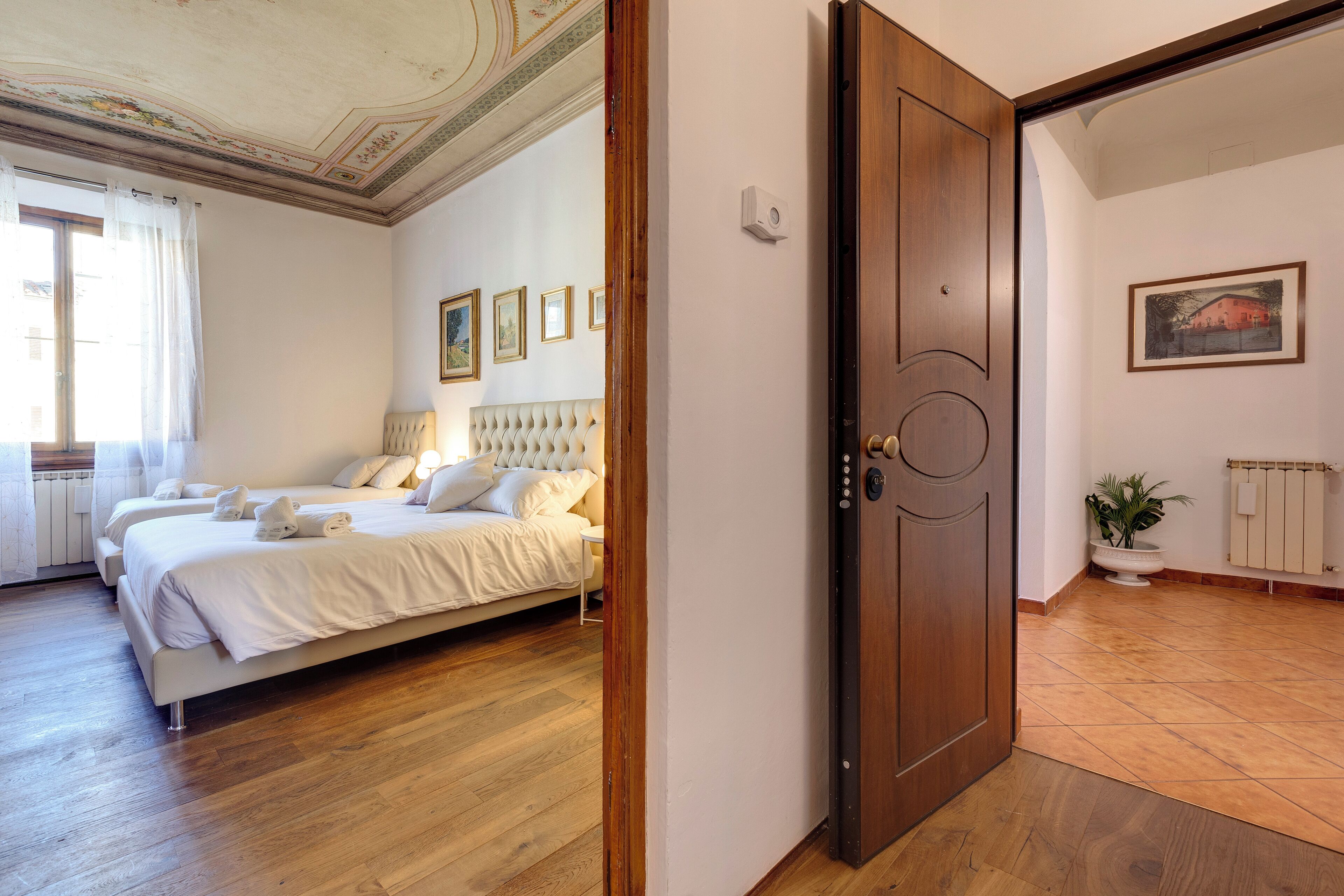 A hotel room with a bed, a wooden door, a radiator, and a framed picture on the wall.