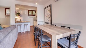 A modern kitchen with a wooden dining table, black chairs, and a white countertop.
