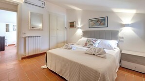 A bedroom with a bed, bedside table, wall-mounted light, and a radiator.
