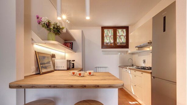 A kitchen with a wooden island, white cabinets, and a window with a lattice design.