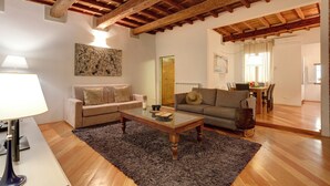 A living room with a wooden ceiling, two sofas, a coffee table, and a rug. - Mamo Florence - San Lorenzo Apartment (Florence)