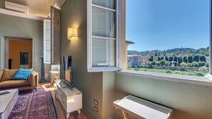 A modern living room with a large window, a sofa, a TV, and a small table. - Mamo Florence - Tintori Luxury Palace (Florence)