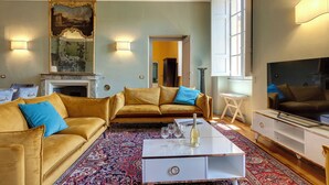 A living room with a sofa, a coffee table, a TV, and a fireplace. - Mamo Florence - Tintori Luxury Palace (Florence)