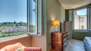 A room with a large window, a wooden dresser, a bed, and a sofa. - Mamo Florence - Tintori Luxury Palace (Florence)