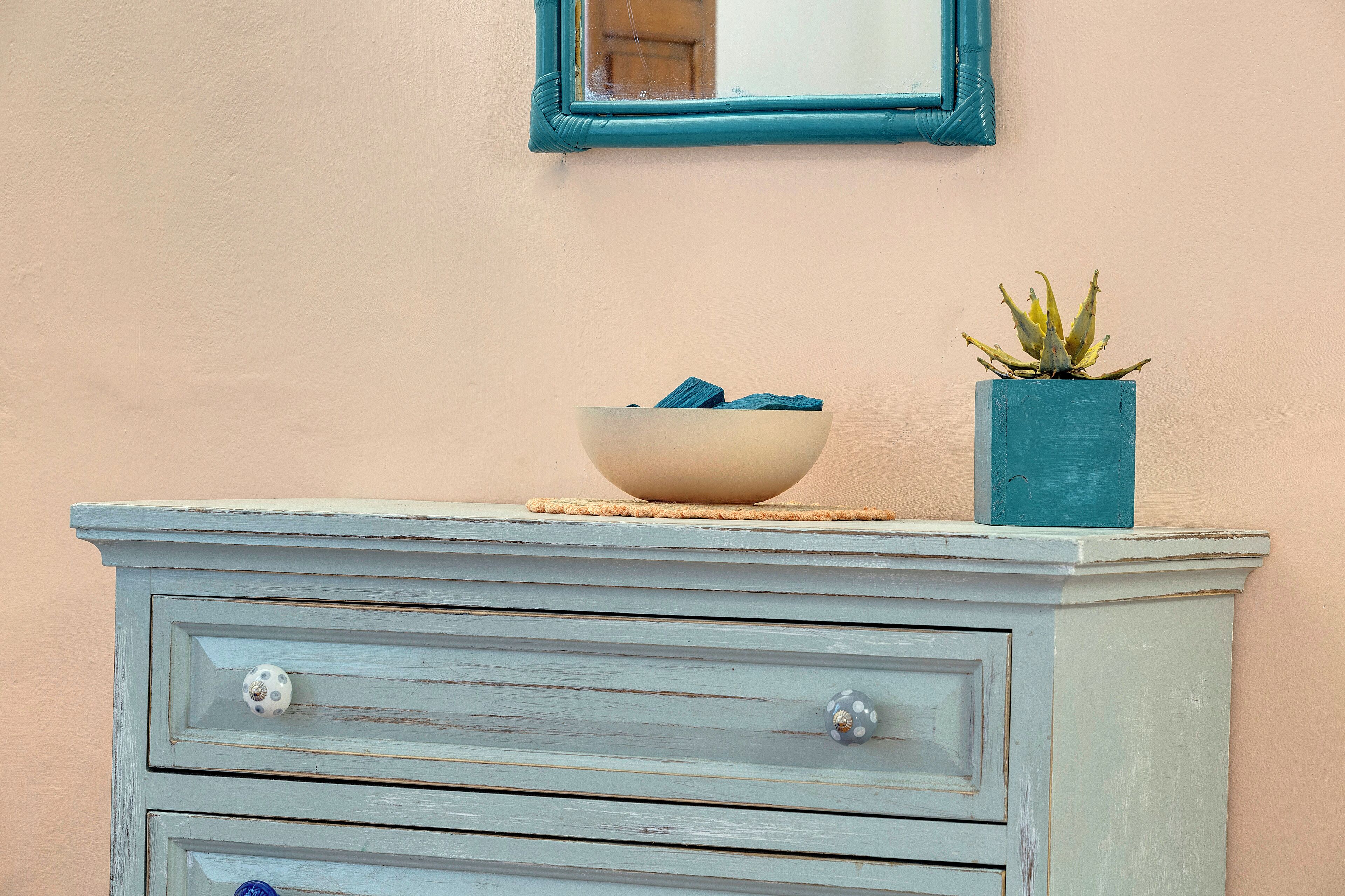 A dresser with a bowl and a plant on top.