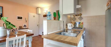 A kitchen with a wooden countertop, white cabinetry, and a tiled backsplash.