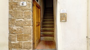 A narrow stairway leading to a wooden door, with a utility box on the wall. - Mamo Florence - Toscanella Apartment (Florence)