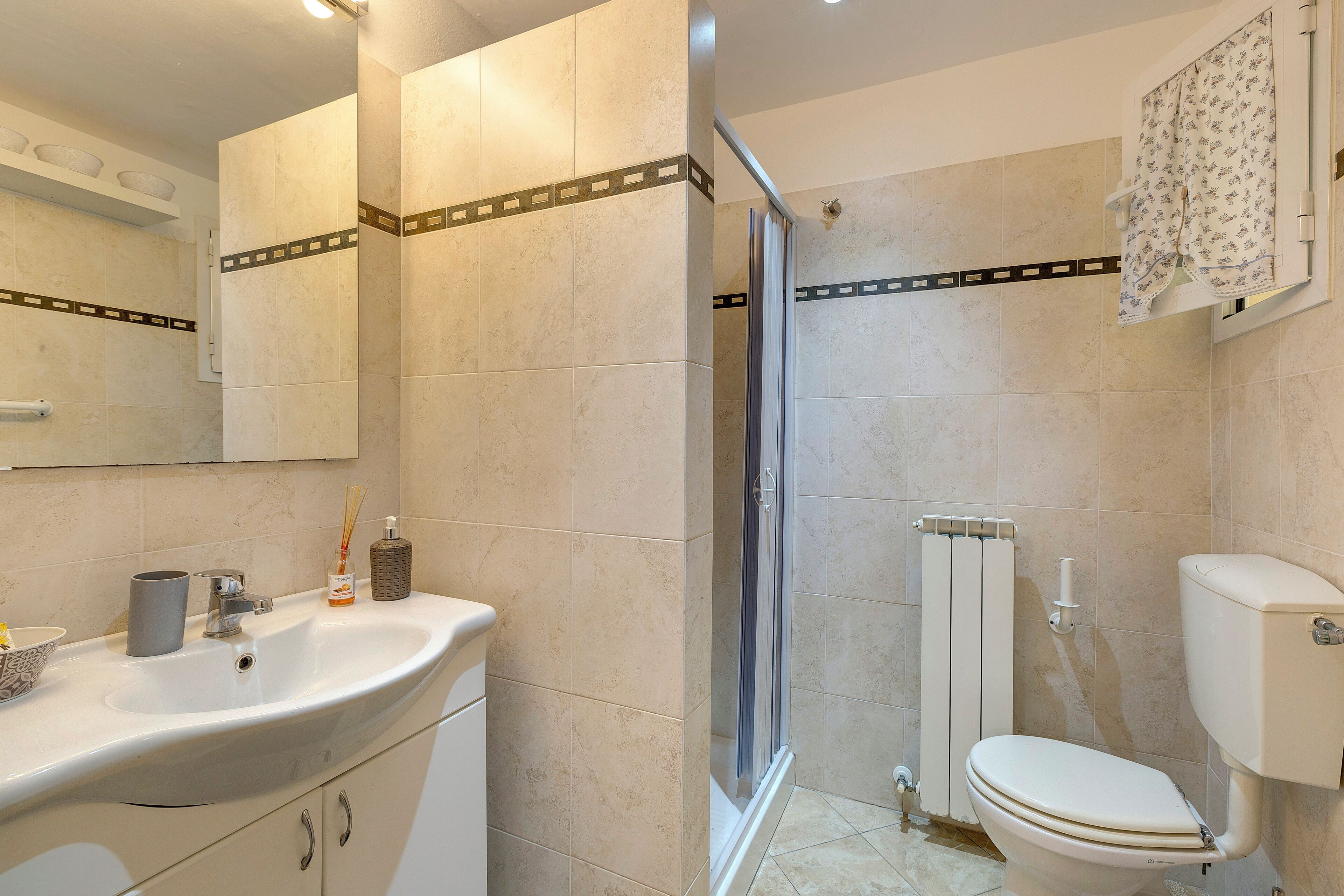 Un baño con lavamanos, espejo, inodoro y ducha.