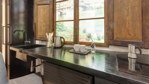 A kitchen with a black countertop, stainless steel appliances, and a window with a view of a bridge and greenery. - Mamo Florence - Vigna Vecchia Studio (Florence)