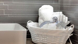 A white woven basket with towels and a white container on a wooden surface against a tiled wall. - Mamo Florence - Vigna Vecchia Studio (Florence)