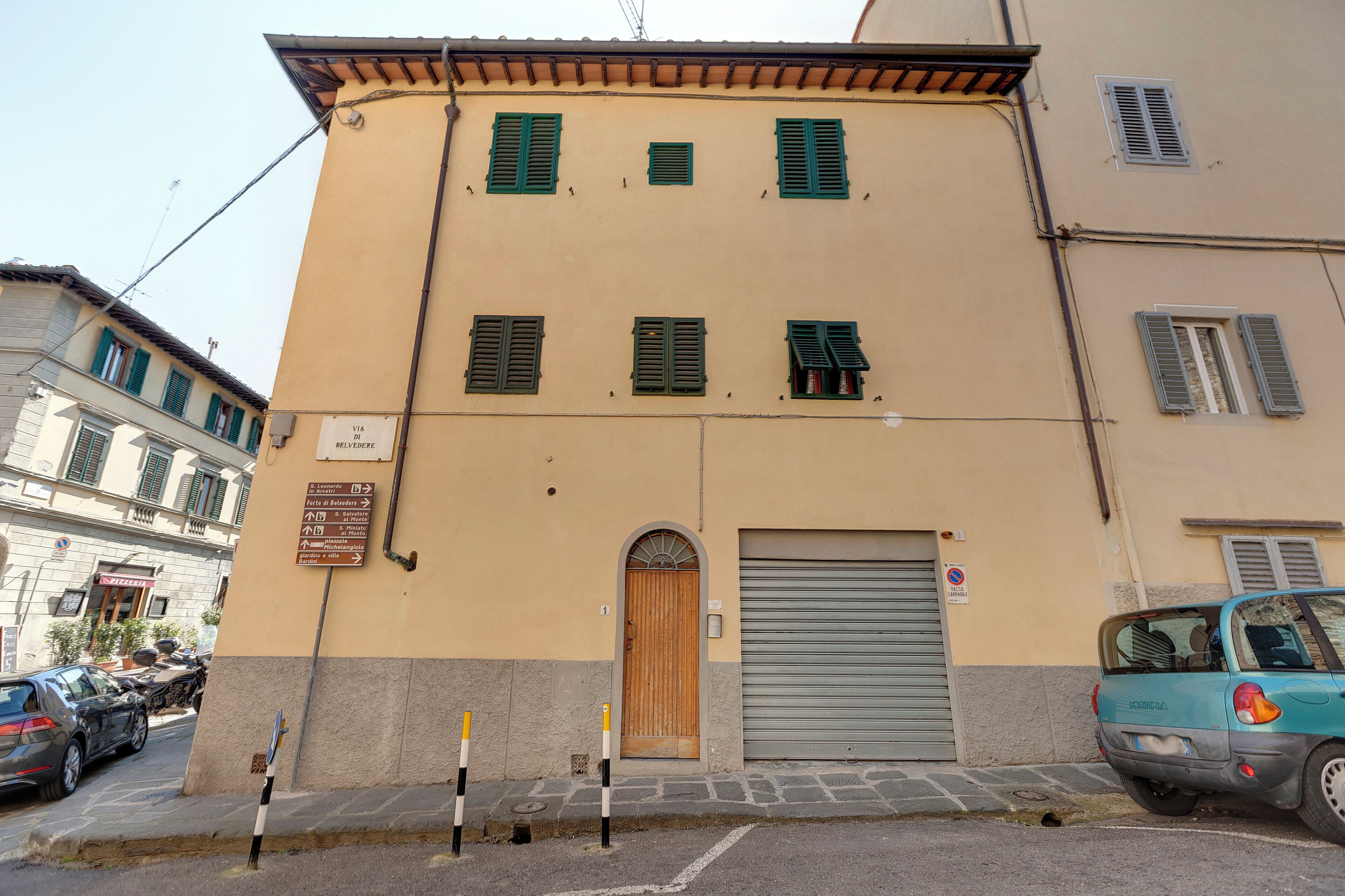 A building with a wooden door, a garage door, and multiple windows with shutters.