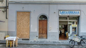 Un bâtiment avec une porte en bois fermée, une enseigne indiquant un service de blanchisserie et un vélo garé à l’extérieur.
