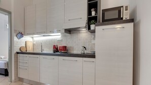 Une cuisine moderne avec des meubles blancs, un four à micro-ondes et une machine à café.