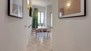 Un espace repas moderne avec une table et des chaises, des œuvres d’art encadrées accrochées aux murs et une plante verte en arrière-plan.