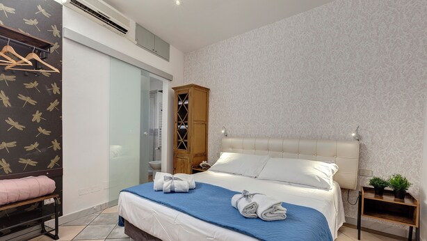 Une chambre à coucher comprenant un lit, une armoire, un banc et une table de chevet agrémentée de plantes.