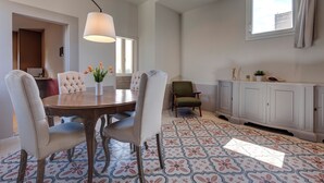 A dining area with a round table, four chairs, a hanging light fixture, and a patterned floor. - Mamo Florence - Zante Aparment (Florence)