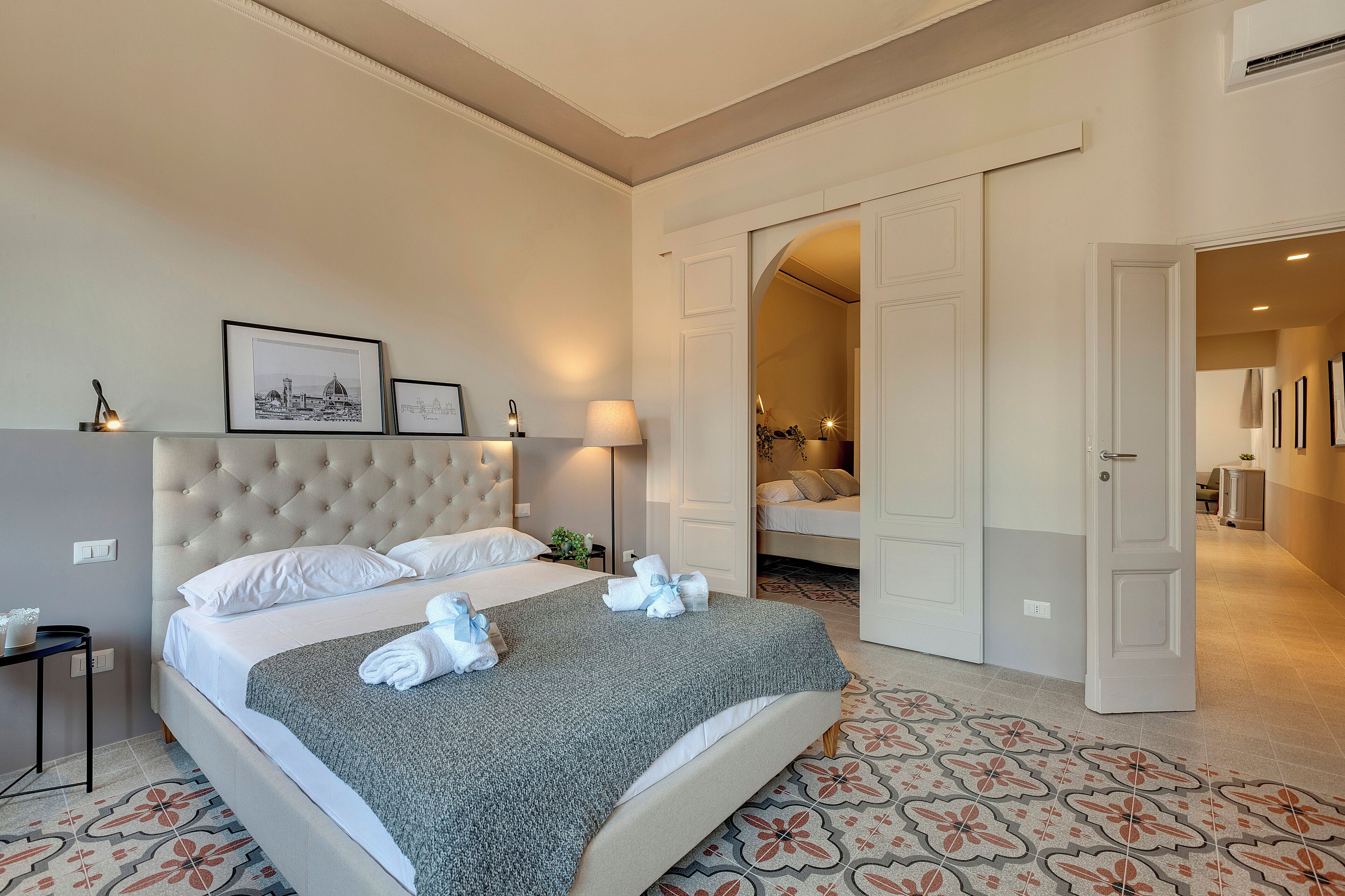 A hotel room with a large bed, a bedside table, a lamp, and framed pictures on the wall.