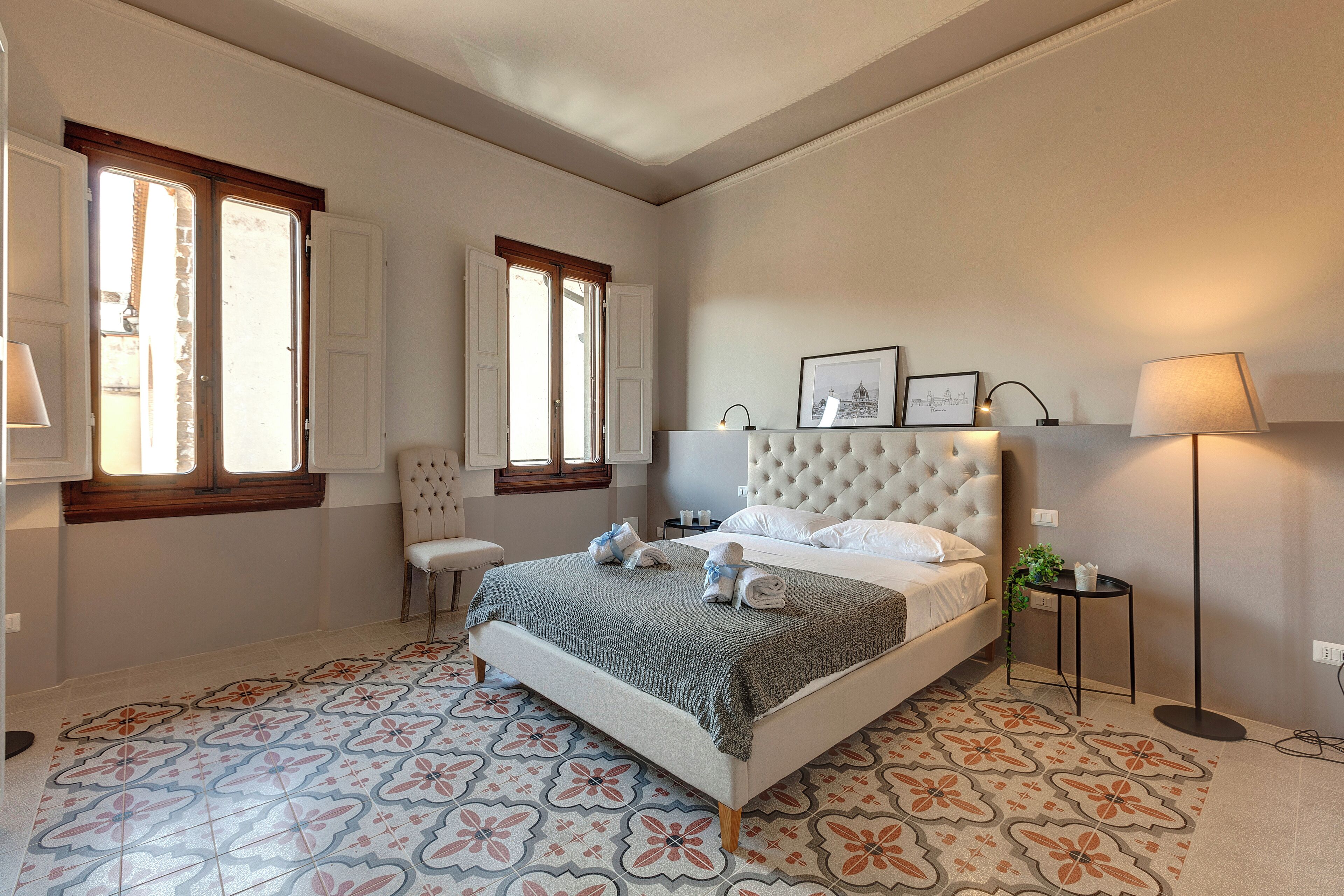 A bedroom with a bed, a chair, a bedside table, and a floor lamp.