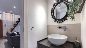 Une salle de bain moderne avec un grand lavabo blanc, un miroir à cadre noir et une petite plante en pot.