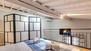 Une chambre avec un lit, un radiateur, une fenêtre avec des rideaux et un téléviseur fixé au mur.