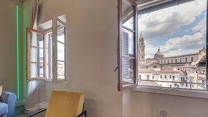 A room with a large window overlooking a historic cityscape, including a prominent church with a dome and bell tower. - Mamo Florence - Sant'Agostino Luxury Apartment (Florence)