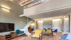 A spacious living area with a modern staircase, a flat-screen TV, and a dining area with chairs and a table. - Mamo Florence - Sant'Agostino Luxury Apartment (Florence)