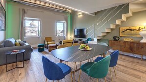 A modern living room with a sofa, dining table, chairs, and a TV. - Mamo Florence - Sant'Agostino Luxury Apartment (Florence)