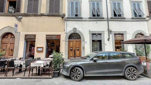 A street with outdoor seating, a parked car, and buildings with signage for a restaurant and a bakery. - Mamo Florence - Sant'Agostino Luxury Apartment (Florence)