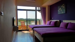 A hotel room with two beds, a balcony with a chair, and a large window offering a view. - Rainbowsea Hostel (Penghu)