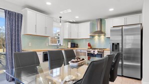 A modern kitchen with white cabinets, stainless steel appliances, and a glass dining table with chairs. - Winchester TN lake house rental, Tims Ford Lake vacation home,private boat ramp (Winchester)