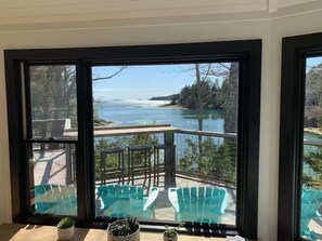 A view from a room with large windows overlooking a pool area with chairs and a small table. - Sea Forever Waterfront, Dog-Friendly, Seasonal Dock, EV charger, 12min Brunswick (Harpswell)